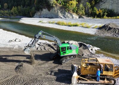 Road builder bucket in use by a river